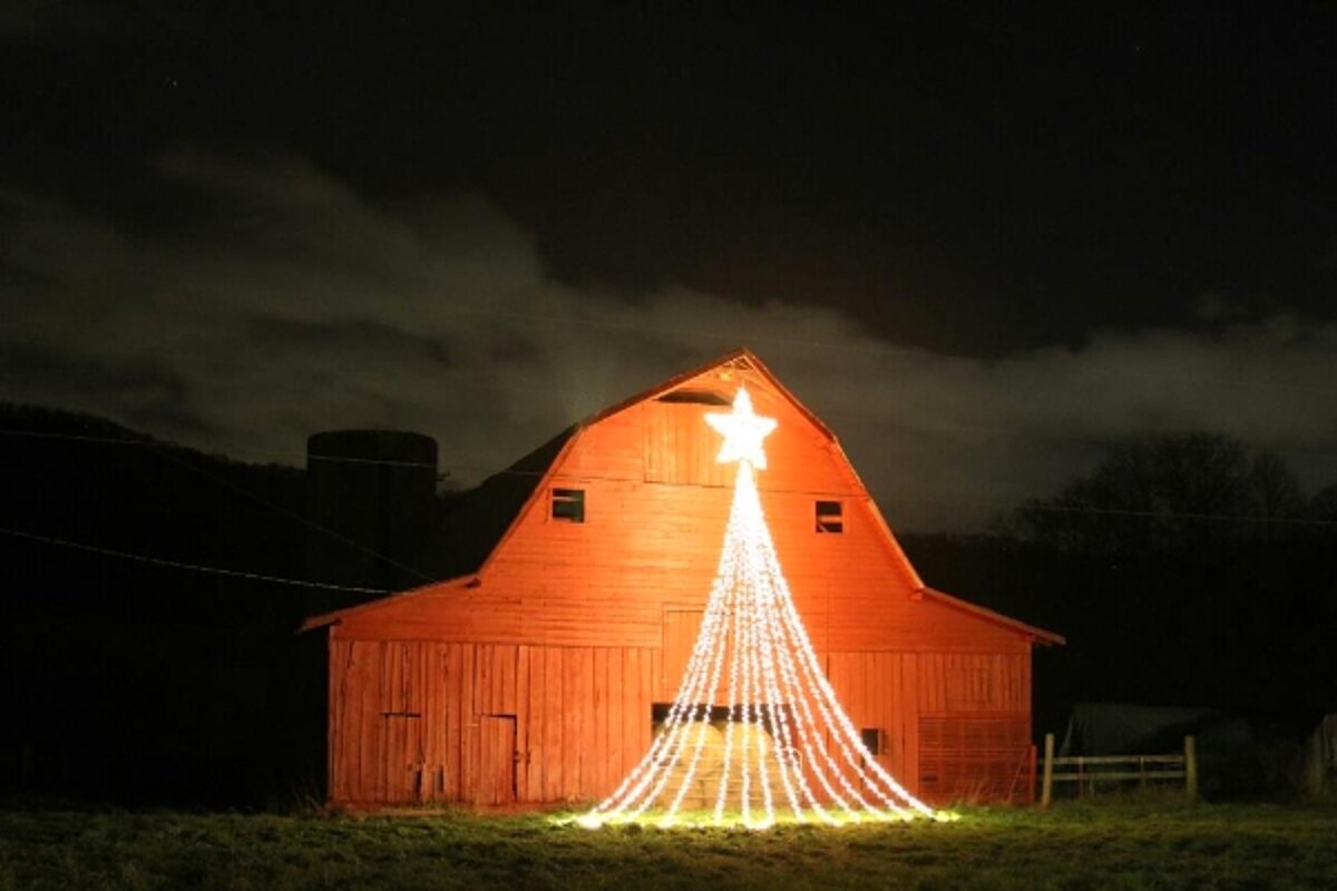 Red barn lit at night with a star and lights forming a Christmas tree shape, Waynesville NC